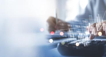 financial information superimposed over hands above keyboard