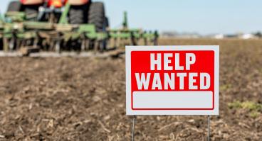 "Help wanted" sign superimposed on plowed land