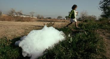 A girl walks by a polluted stream in Cuenavaca.