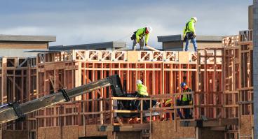  A crew of construction workers atop wooden structures, building a multistory apartment complex in East Mesa, Arizona.