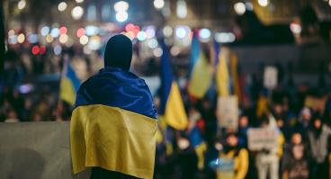 Person standing in crowd wearing Ukrainian flag