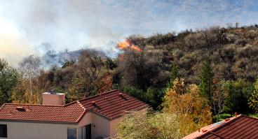 Wildfire erupts near houses on a hill