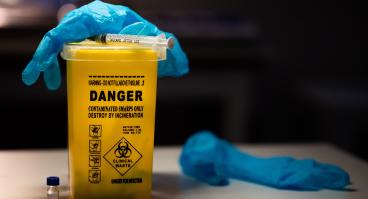 Gloves and syringe on top of sharps container