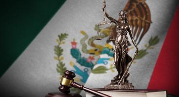 Mexico flag with statue of lady justice, constitution and judge hammer on black drapery. Concept of judgement.