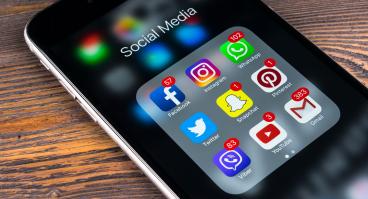 Apple iPhone 7 on wooden table with icons of social media