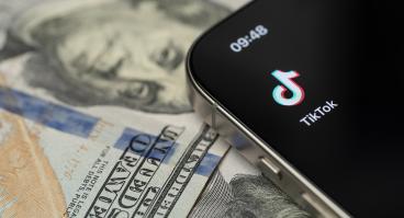 TikTok app on smartphone screen with dollar background