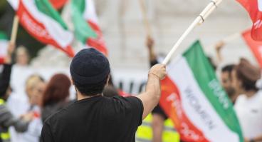 Man holding Iranian flag at women’s rights protest