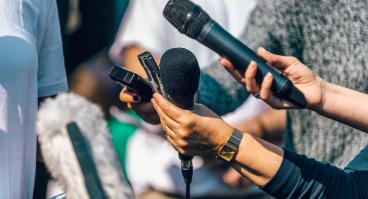 Reporters hold up microphones