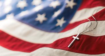 Christian cross necklace on American flag.