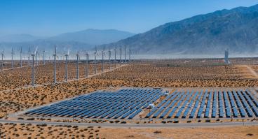 solar panels and wind turbines in desert landscape