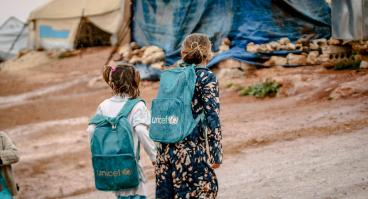 Refugee girls wearing UNICEF backpacks