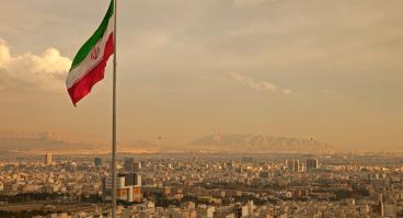 Iran Flag in the Wind Above Skyline of Tehran 