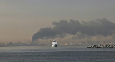 A yacht sails past a plume of smoke rising from the port of Jebel Ali following a reported Iranian strike in Dubai on March 1, 2026.