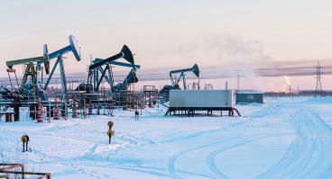Oil Field. Winter industrial landscape with an oil pump and torch in the background. 