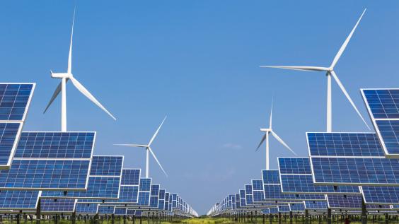Windmills and solar panels in a grass field.