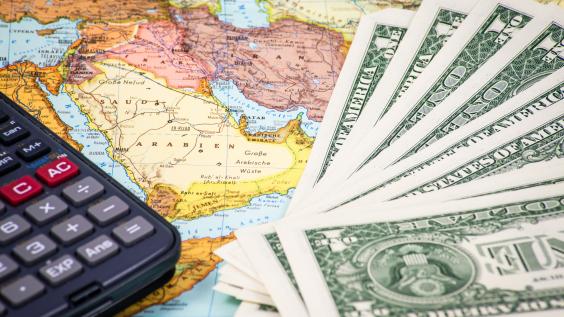 Money and a calculator rest on top of a map of the Middle East.