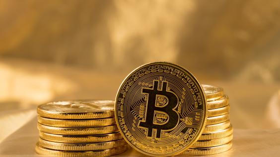 A Bitcoin leans against two stacks of Bitcoins.
