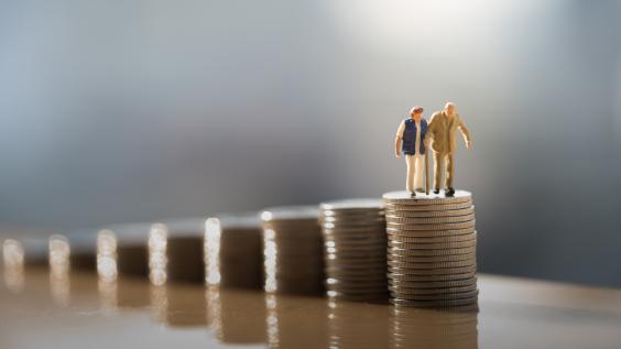 Two old people standing on a stack of coins.