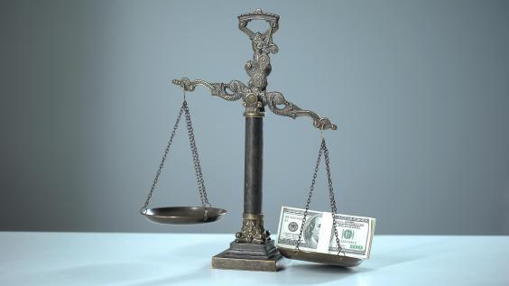 Money weighs down a balance scale.