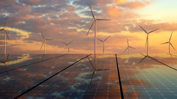 Wind turbines and solar panels against a sunset.