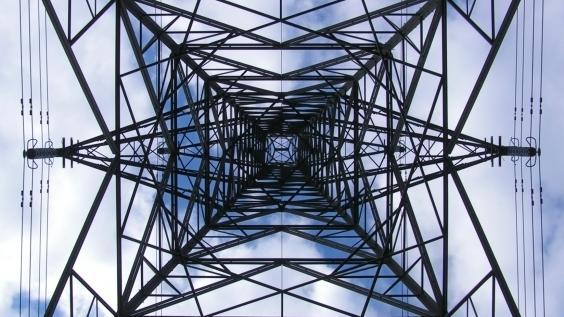 This photo shows an upward view of a transmission tower.