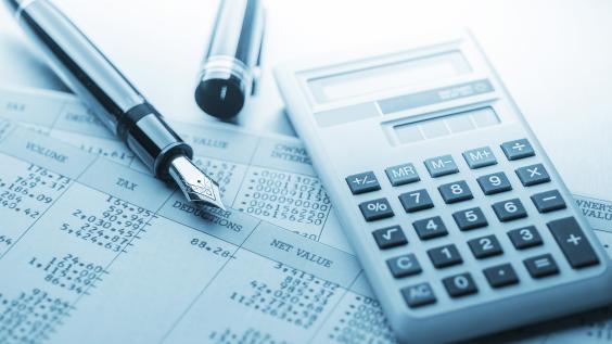 A calculator and fountain pen lie on top of accounting documents.