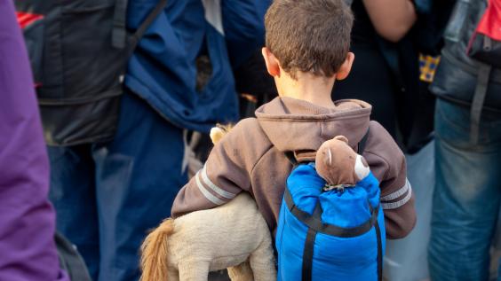 A refugee boy holds a stuffed animal.