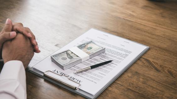 Wad of cash on top of a contract