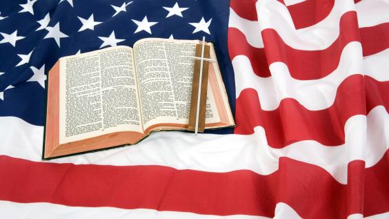 A Bible and the Christian cross on top of an American Flag.