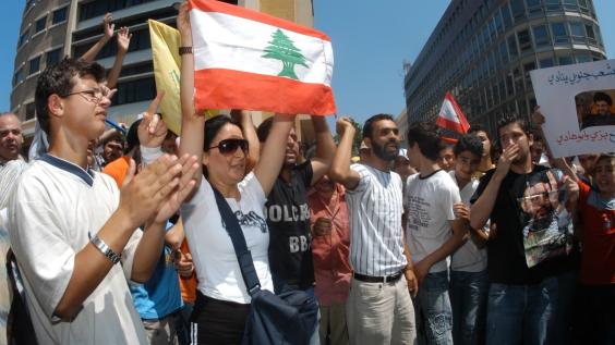 A protester holds up the Lebanese flag amongst other protesters.