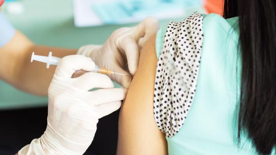 A woman receives a vaccine in her left arm.