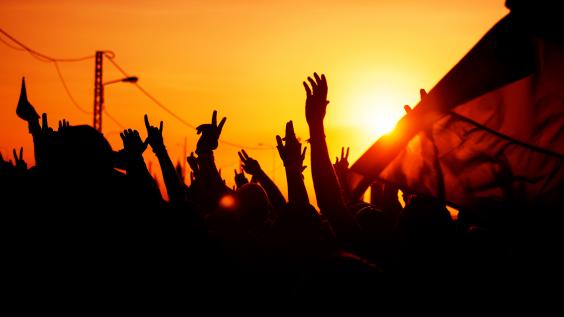 Hands raise up against a sunset.