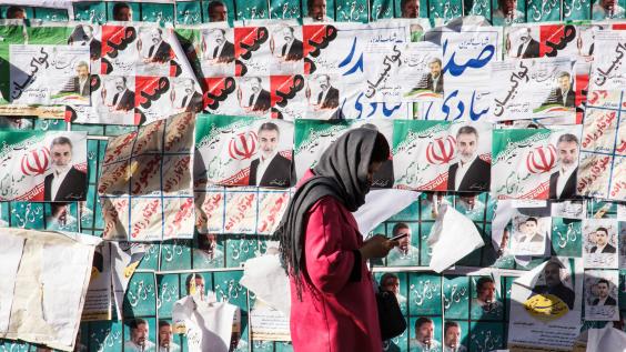 Woman in Iran stands in front of election posters