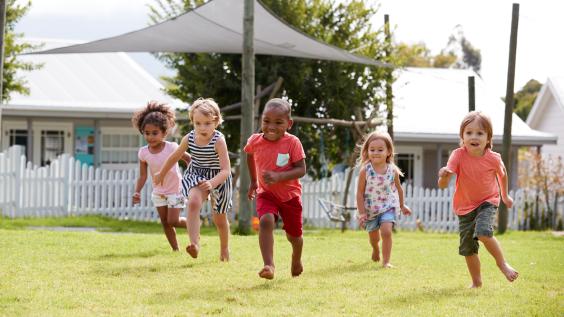 Five children run across a lawn.