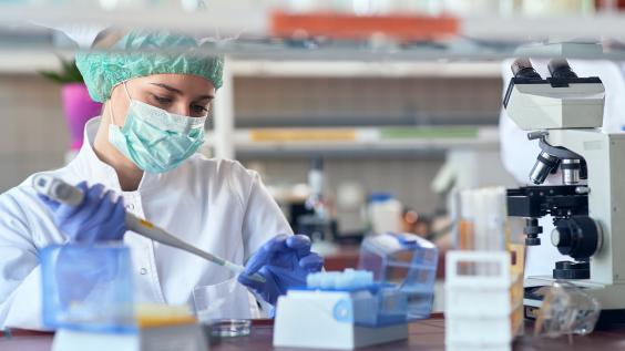 A scientist prepares a pipette in a lab.
