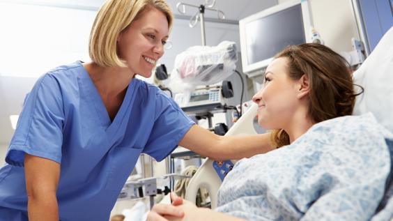 A nurse and a patient smile at each other.