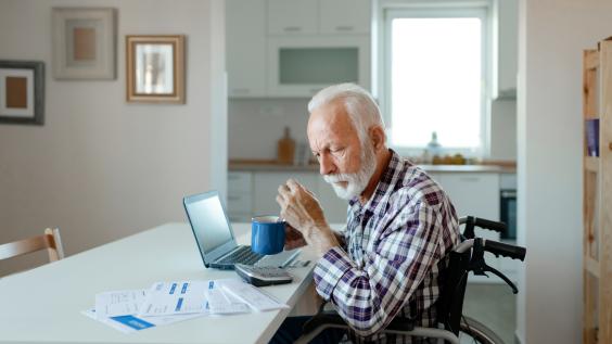 An elderly man in a wheelchair reviews billing statements.