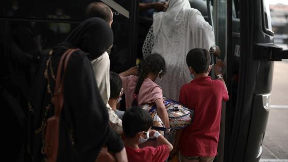 A family of Afghan refugees board a bus.