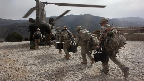 Military troops carry supplies to a helicopter in Afghanistan.
