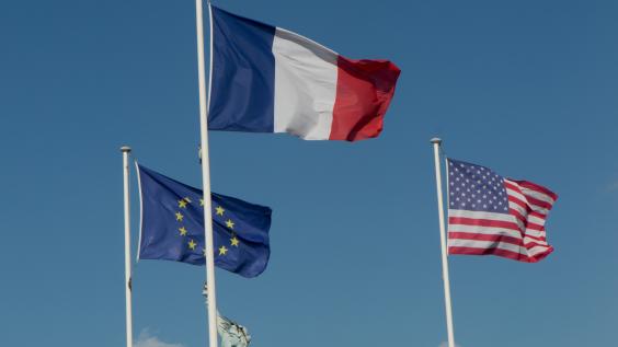 The flags of the EU, France, and the United States wave together in the air.