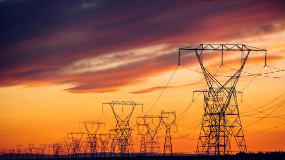 Power lines and transmission towers against a sunset.