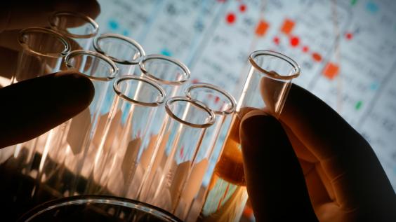 A scientist picks up test tubes from a rack.