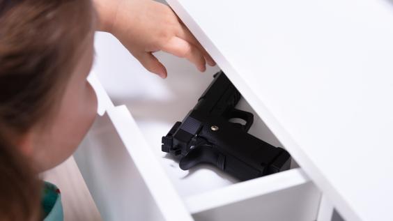 Small child reaches into drawer with firearm