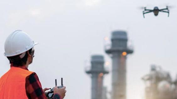 person in safety vest flying drone near power plant