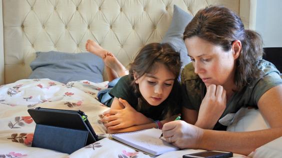 A mother teaches her daughter at home.