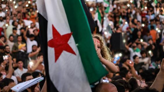 A young girl raises the Syrian opposition flag