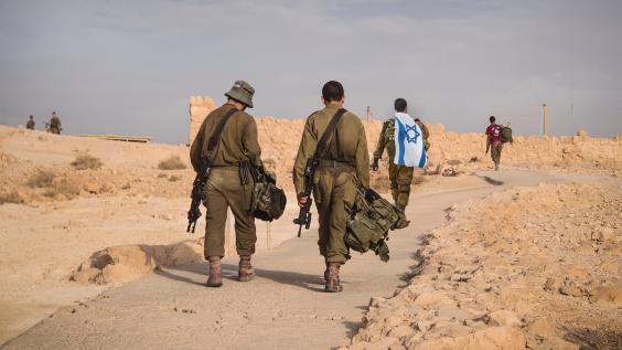 Several soldiers of Israel army walking with Israel national flag
