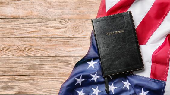 Holy Bible and American flag on wooden background