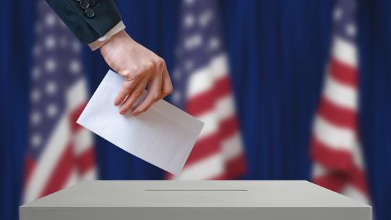 Voter holds envelope in hand above vote ballot
