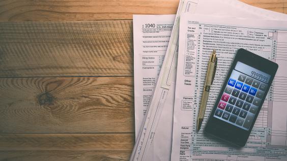 tax forms on table with calculator and pen on top